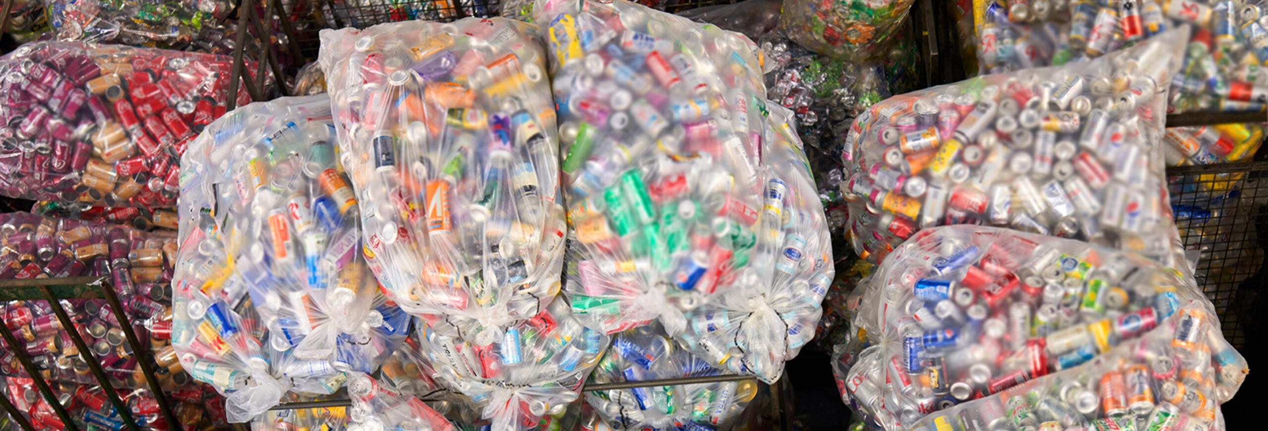 Many clear plastic bags full of recyclable beverage cans stacked together.