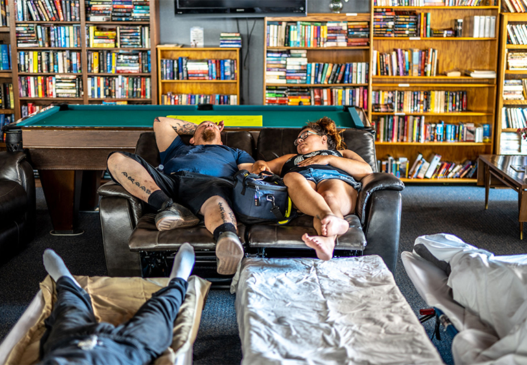 People relaxing on sofas and cots at an Oregon cooling center during a heat wave.
